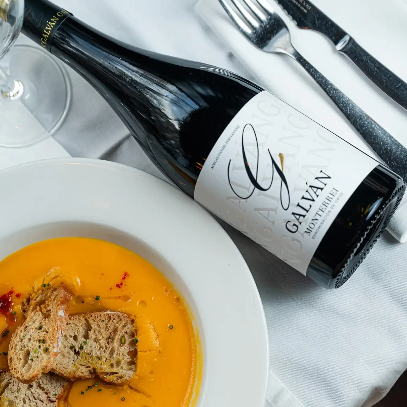 Botella de vino Galván junto a una crema mediterránea